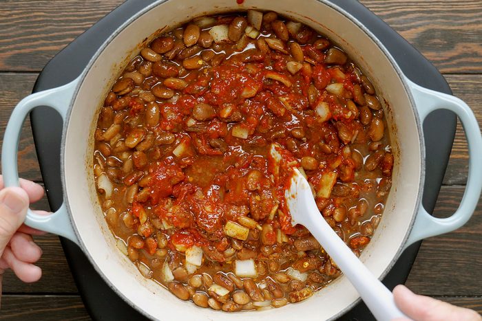 Adding other ingredients to boiled beans in a dutch oven