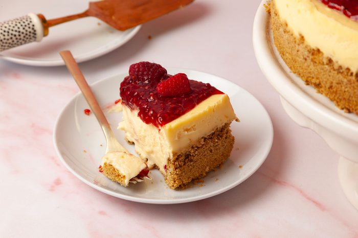 One slice of Taste of Home Raspberry Cheesecake, light pink surface, white and black pie server, full yield peaking in