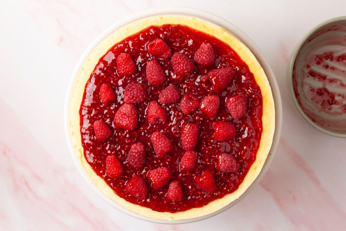 Step 6 of Taste of Home Raspberry Cheesecake is to loosen the cheesecake from the springform pan using a knife, then remove the pan’s rim. Spread the chilled raspberry topping over the cheesecake and garnish with the remaining fresh raspberries.