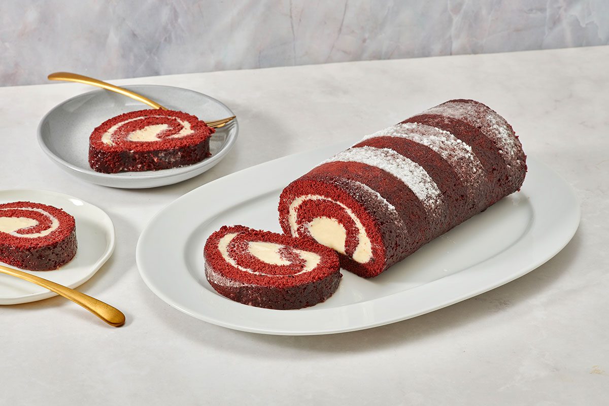 Red velvet cake roll served on a platter with a slice removed