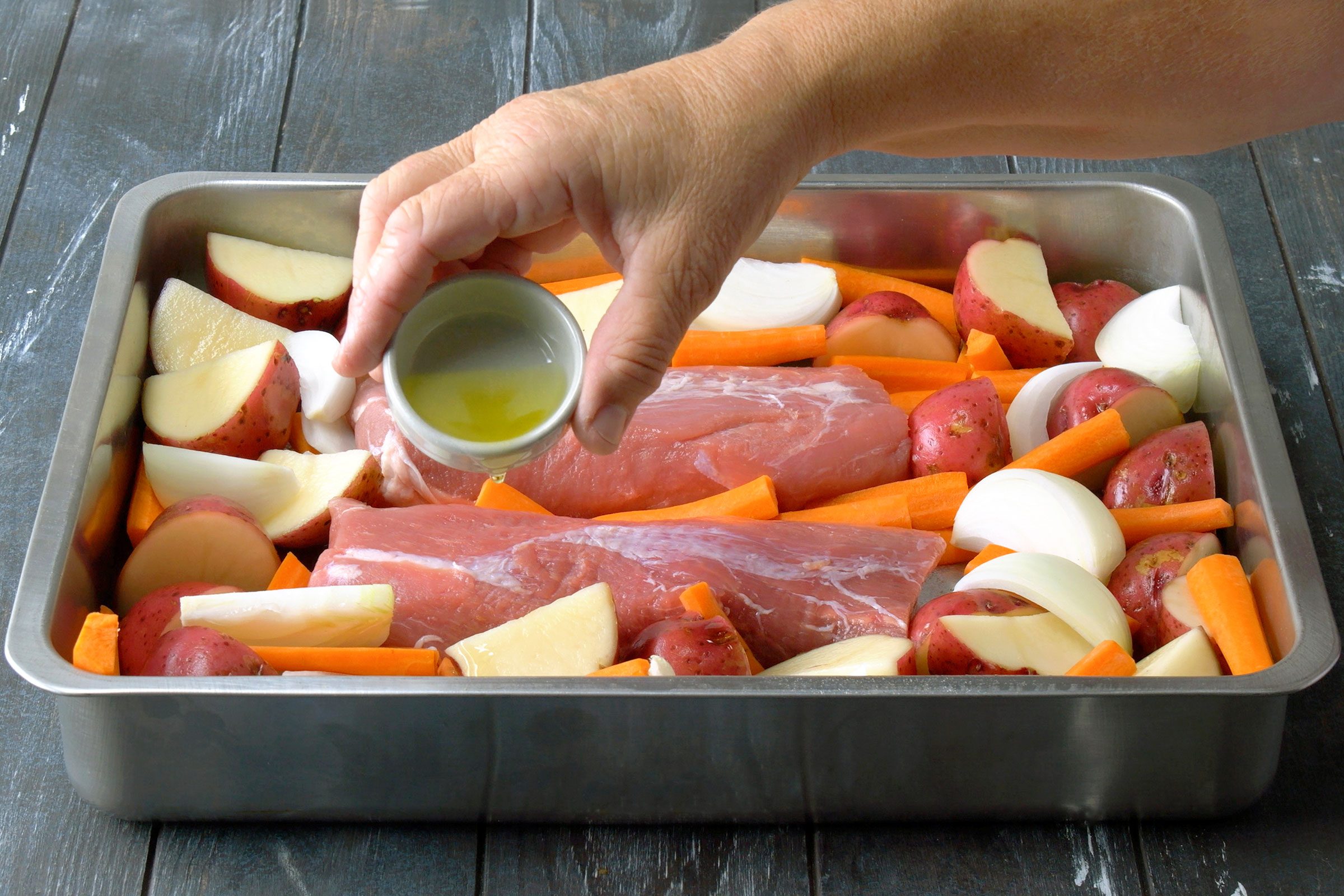 Drizzling vegetables and the pork with olive oil