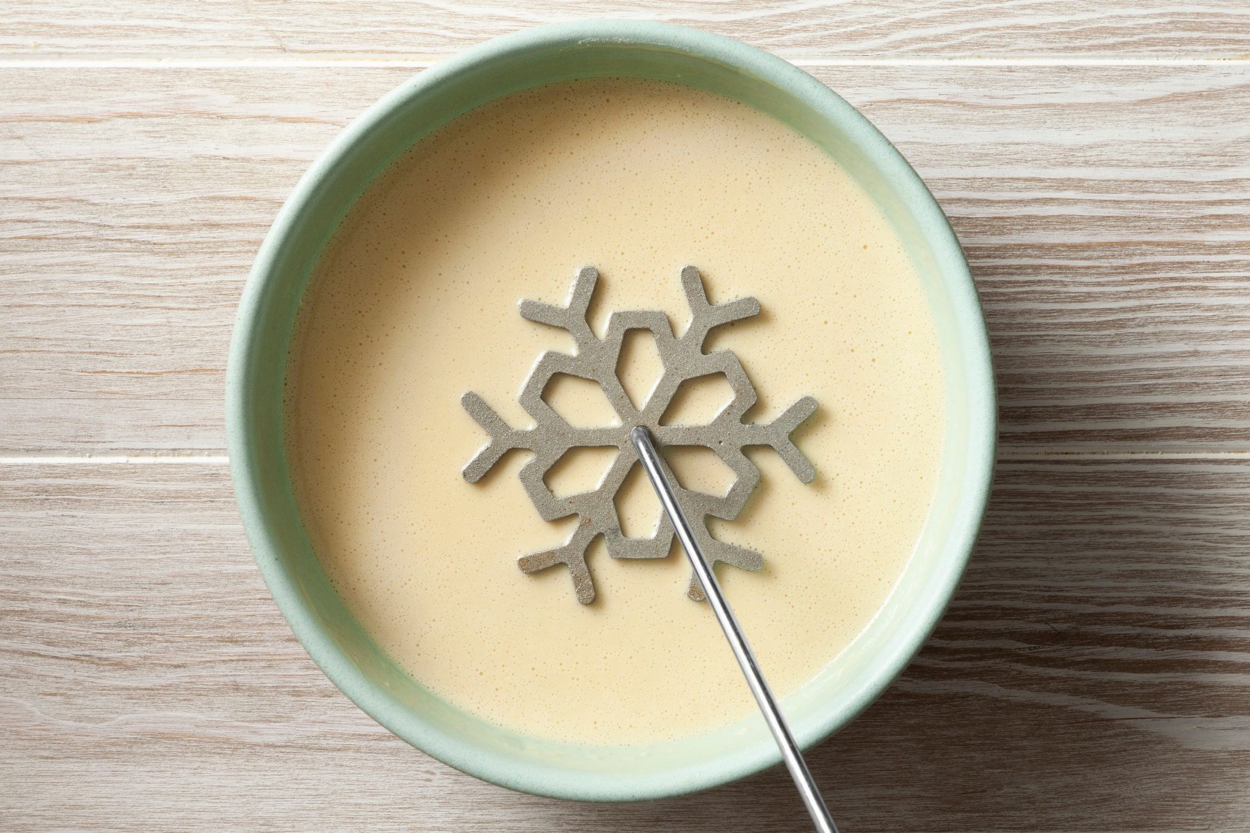 Rosette iron is being dipped into cookie batter.