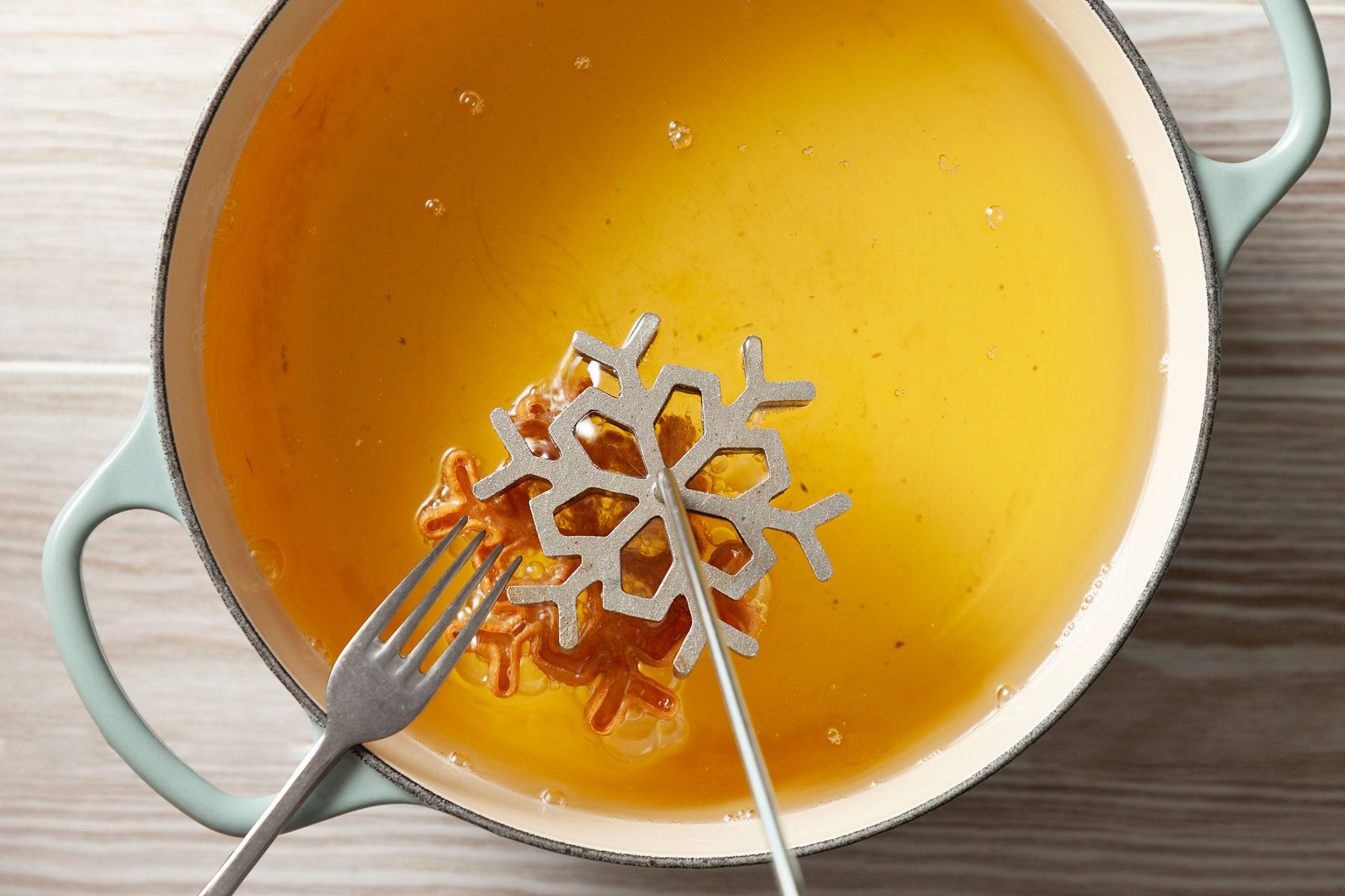 Fork is being used to loosen the cookie from the rosette iron.