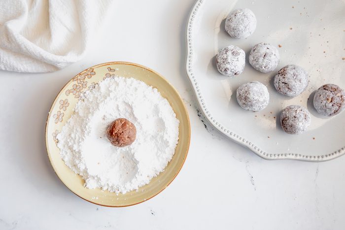 Overhead shot for Taste of Home Rum Balls, with rum balls being tossed in powdered sugar.