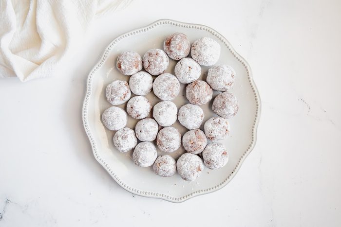 Overhead shot for Taste of Home Rum Balls, all rum balls tossed in powdered sugar on a plate.