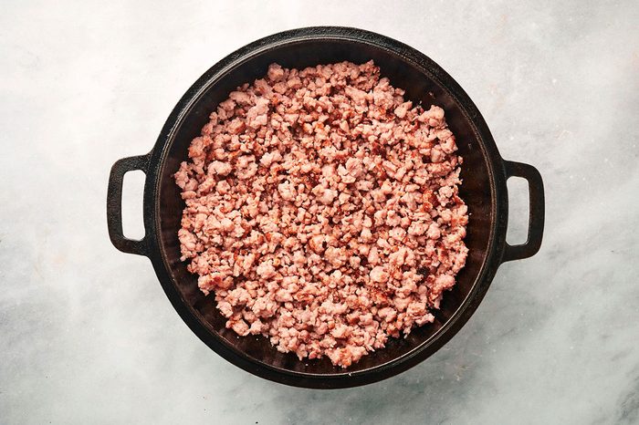 Browning the sausage in a large cast iron skillet for the Sausage Hash recipe by Taste of Home
