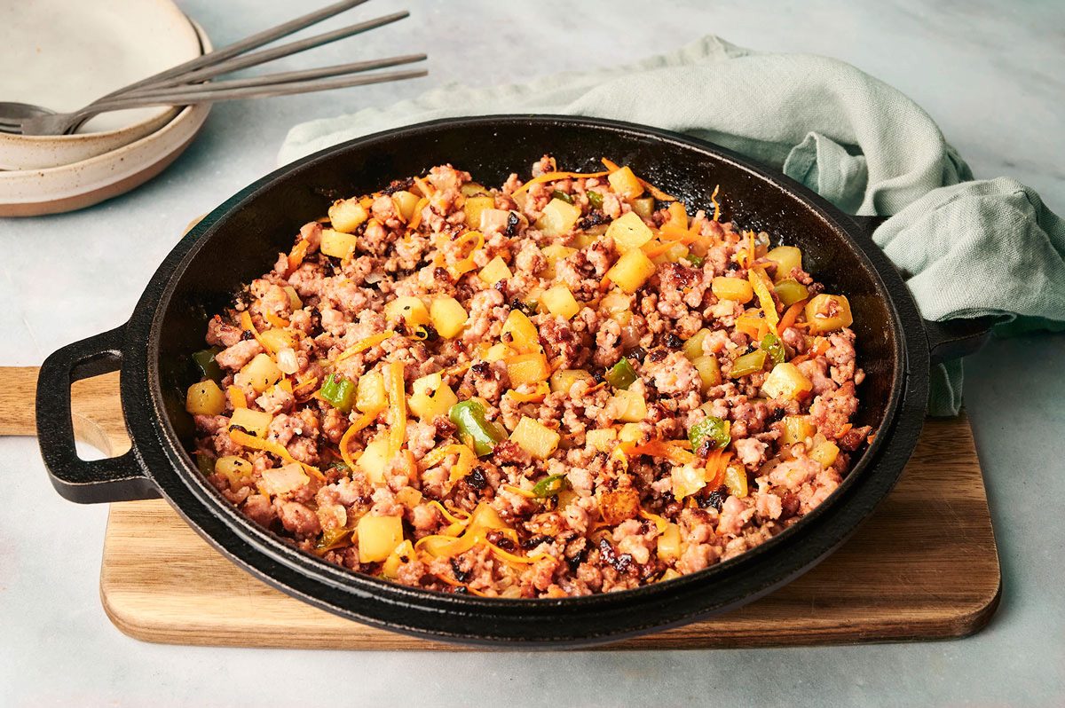 Sausage Hash on a marble table prepared in a large cast iron skillet, recipe by Taste of Home
