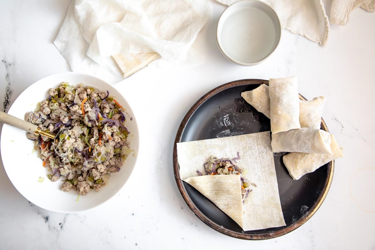 Overhead shot for Taste of Home Sausage Egg Rolls, putting filling into egg roll wrappers.