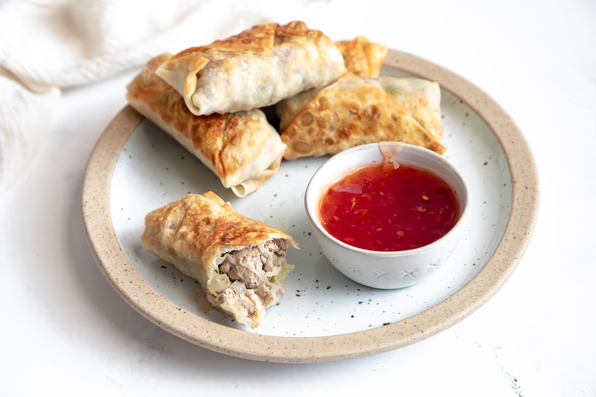 Close up beauty shot for Taste of Home Sausage Egg Rolls, egg rolls on a plate with sweet chili sauce.