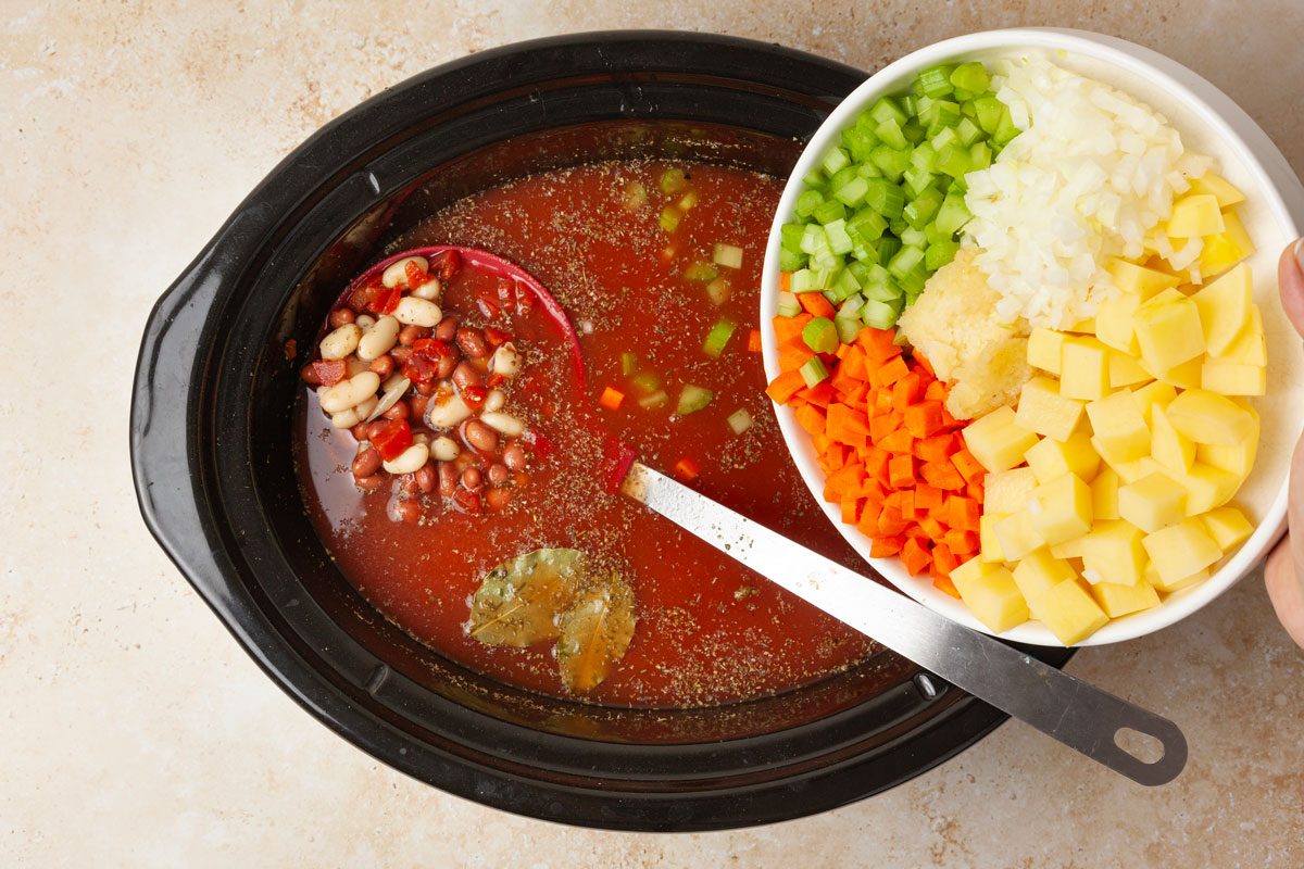 Process shot of Slow-Cooker Minestrone soup, adding ingredients into slow cooker