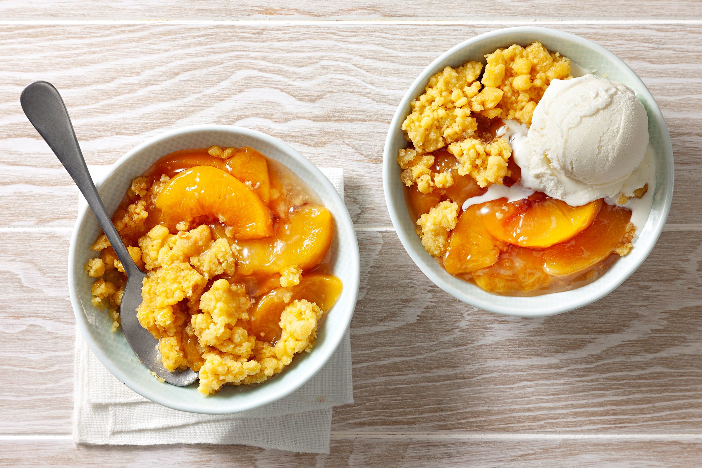 Slow cooker peach cobbler served with vanilla ice cream