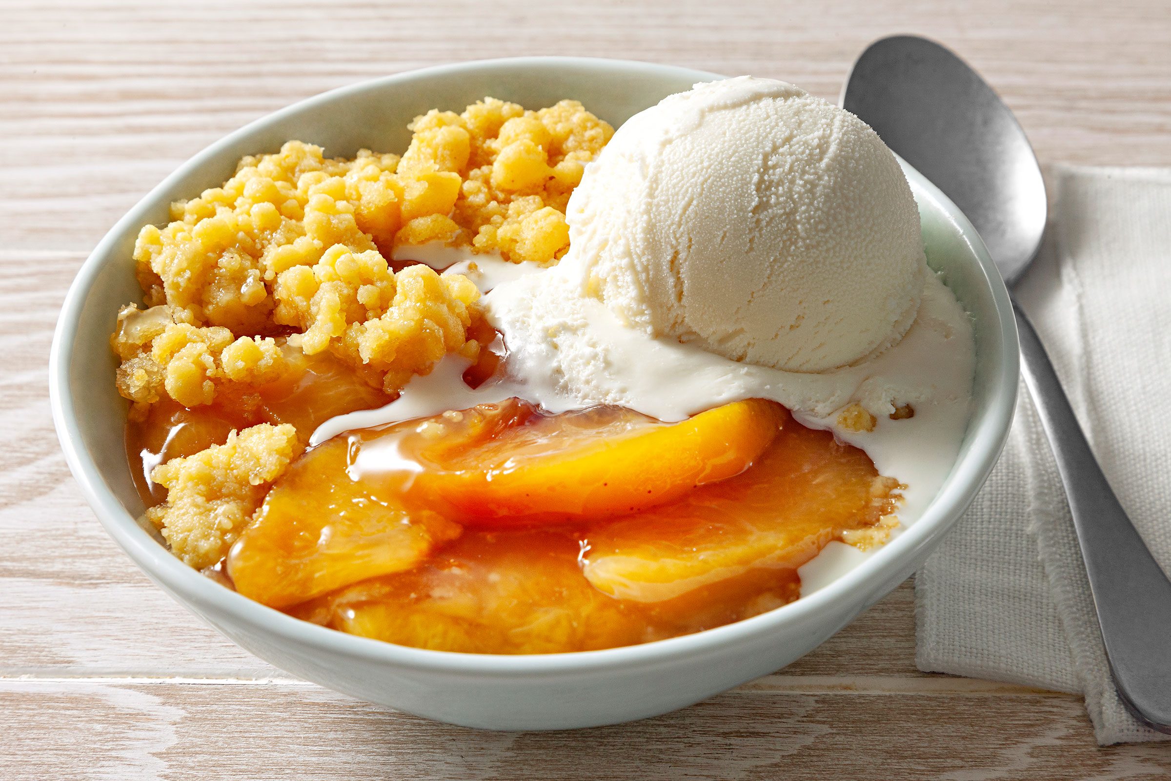 Slow Cooker Peach Cobbler in a big bowl served with vanilla ice cream