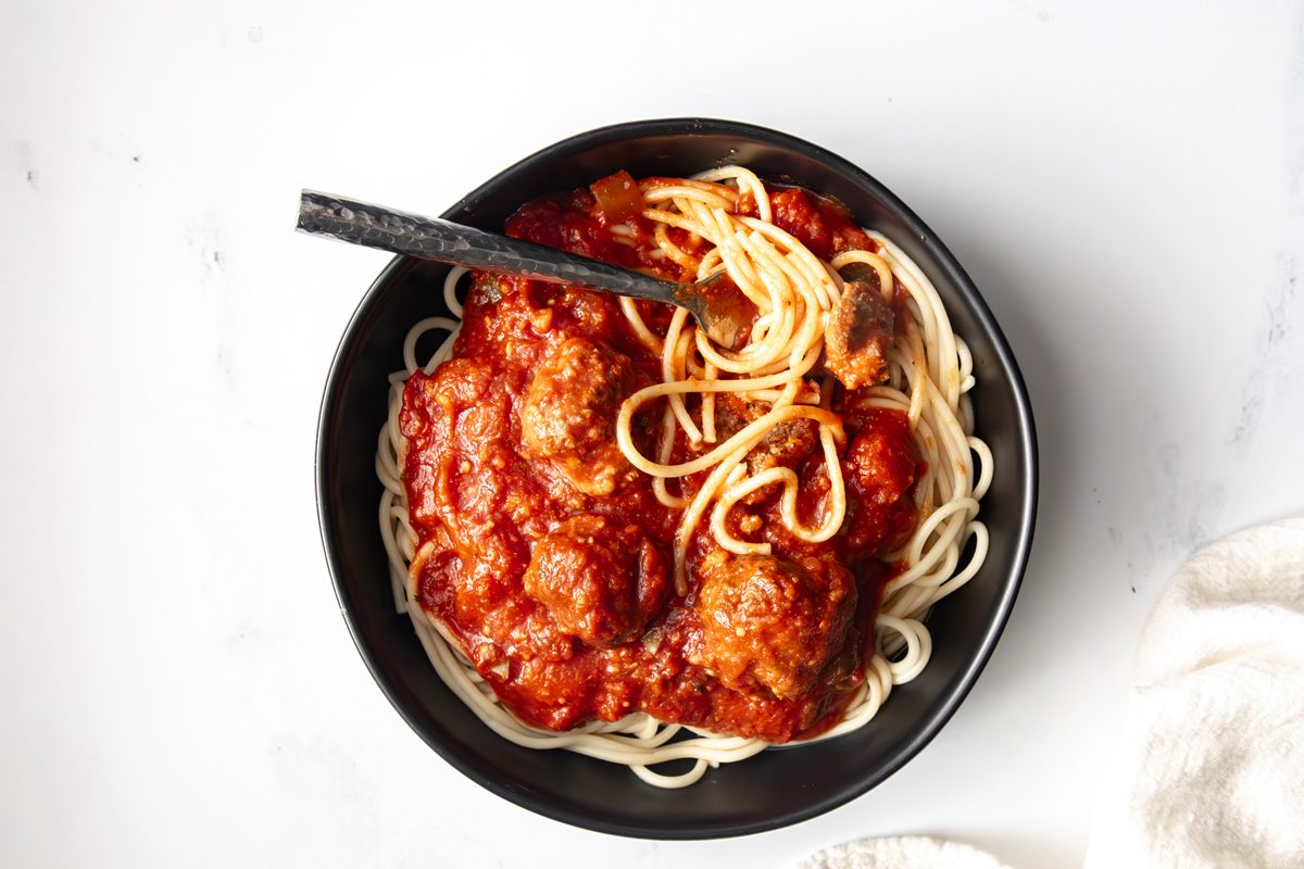 Overhead beauty shot shot for Taste of Slow-Cooker Spaghetti and Meatballs being served in a black bowl.