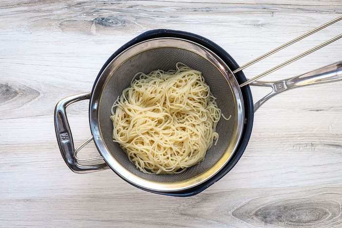 Draining angel hair pasta for smoked sausage and pasta skillet meal.