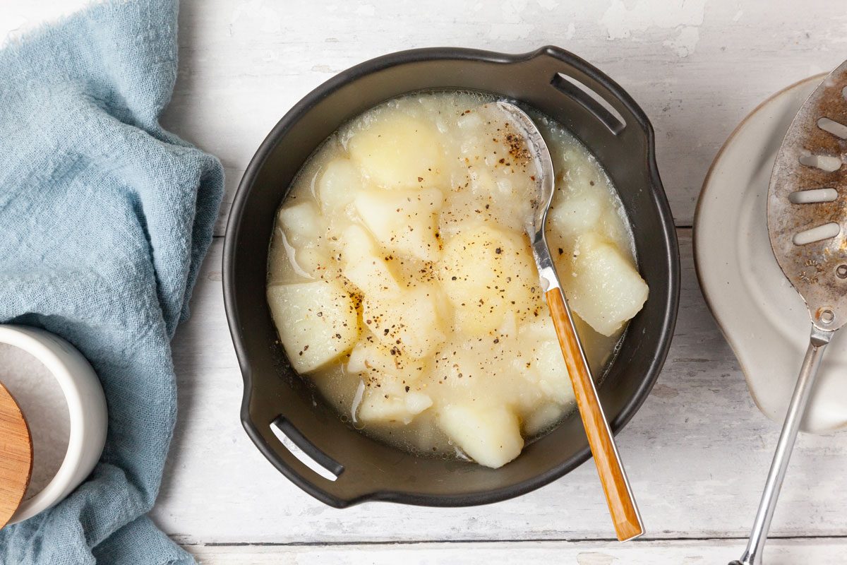 One serving of Taste of Home Stewed Potatoes in black bowls, topped with pepper