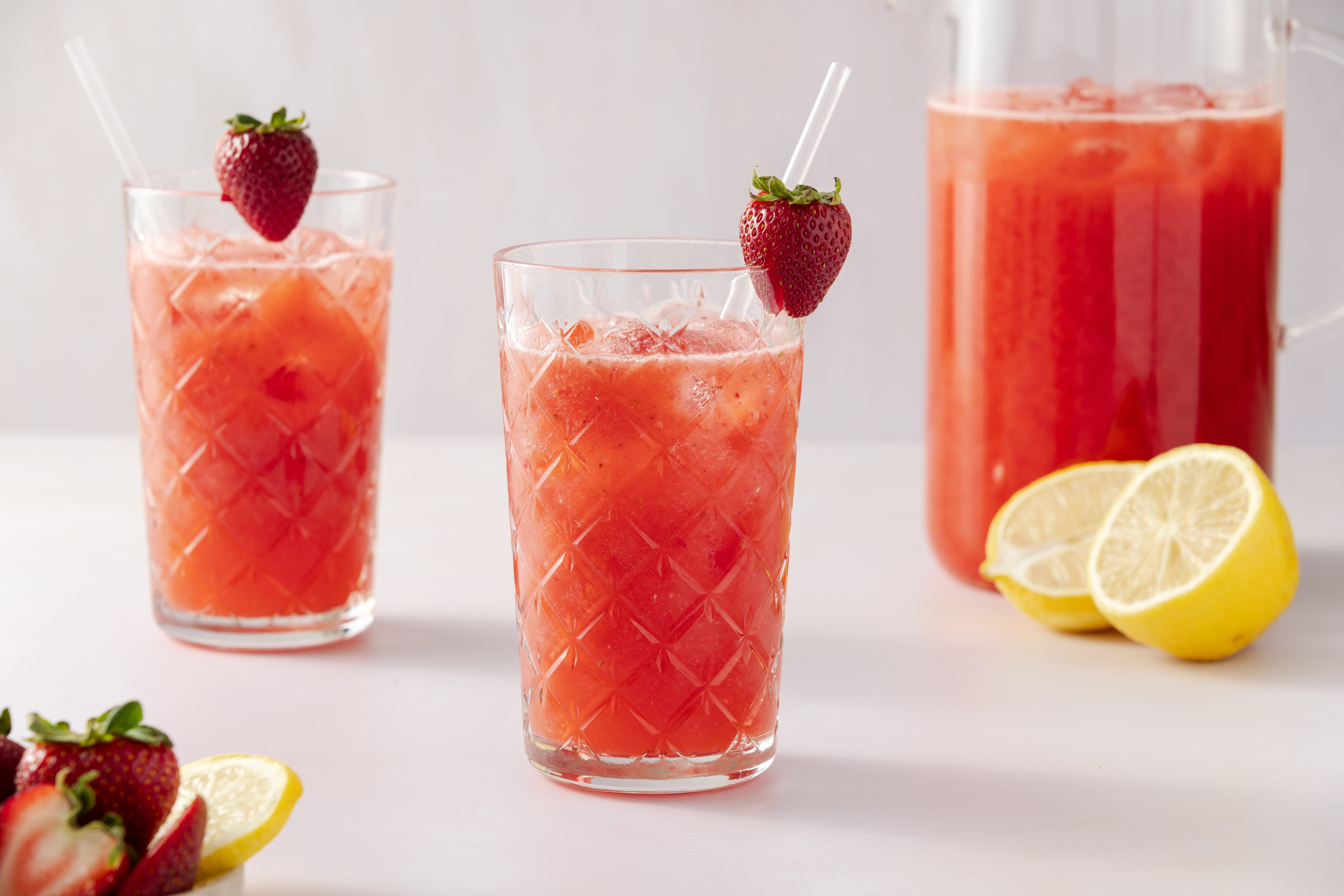 Strawberry drink served in tall glasses and pitcher of drink in the background.
