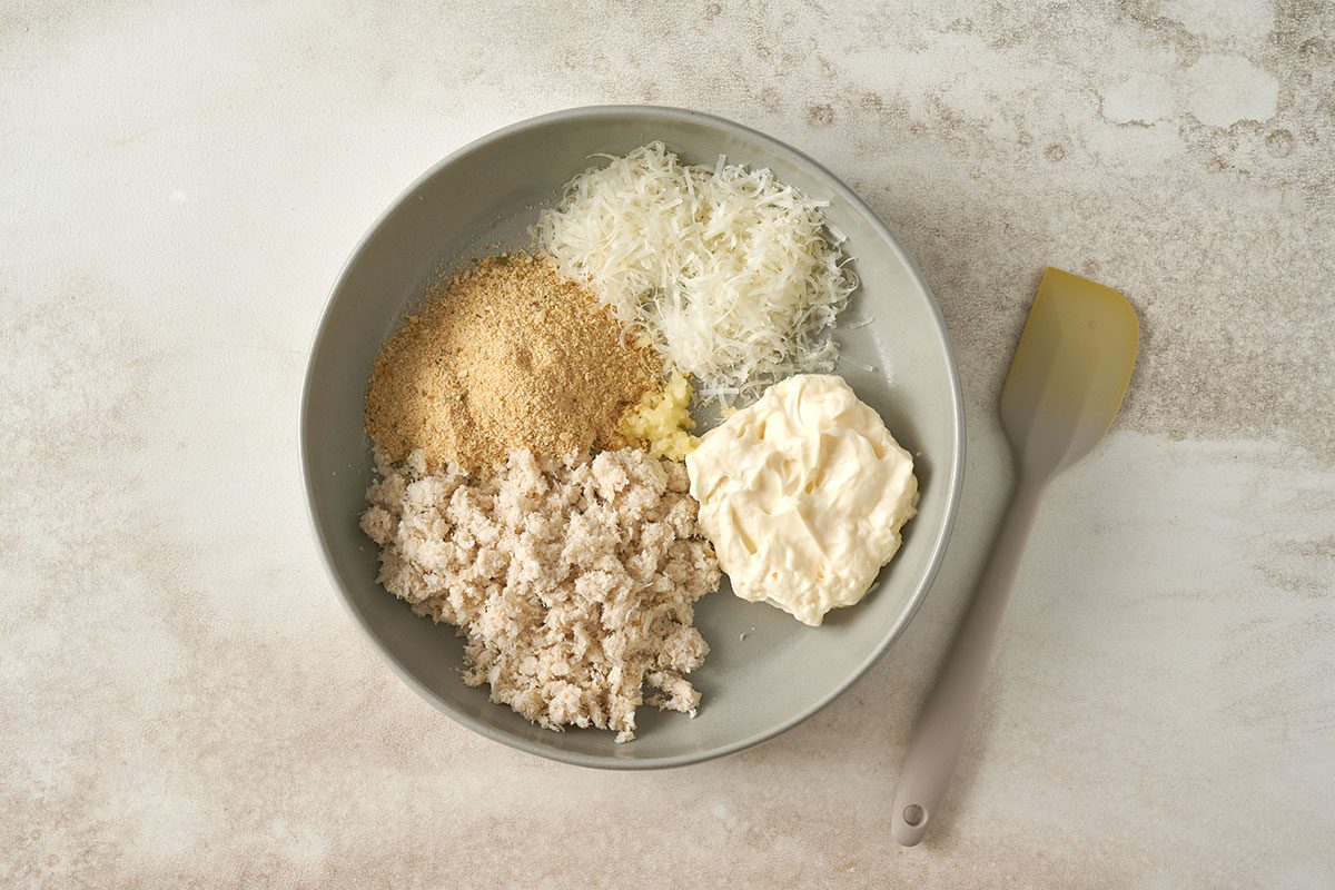 Combining crabmeat, mayonnaise, bread crumbs, Parmesan cheese, and garlic to stuff the mushroom caps for the Stuffed Mushrooms with Crabmeat recipe, by Taste of Home.