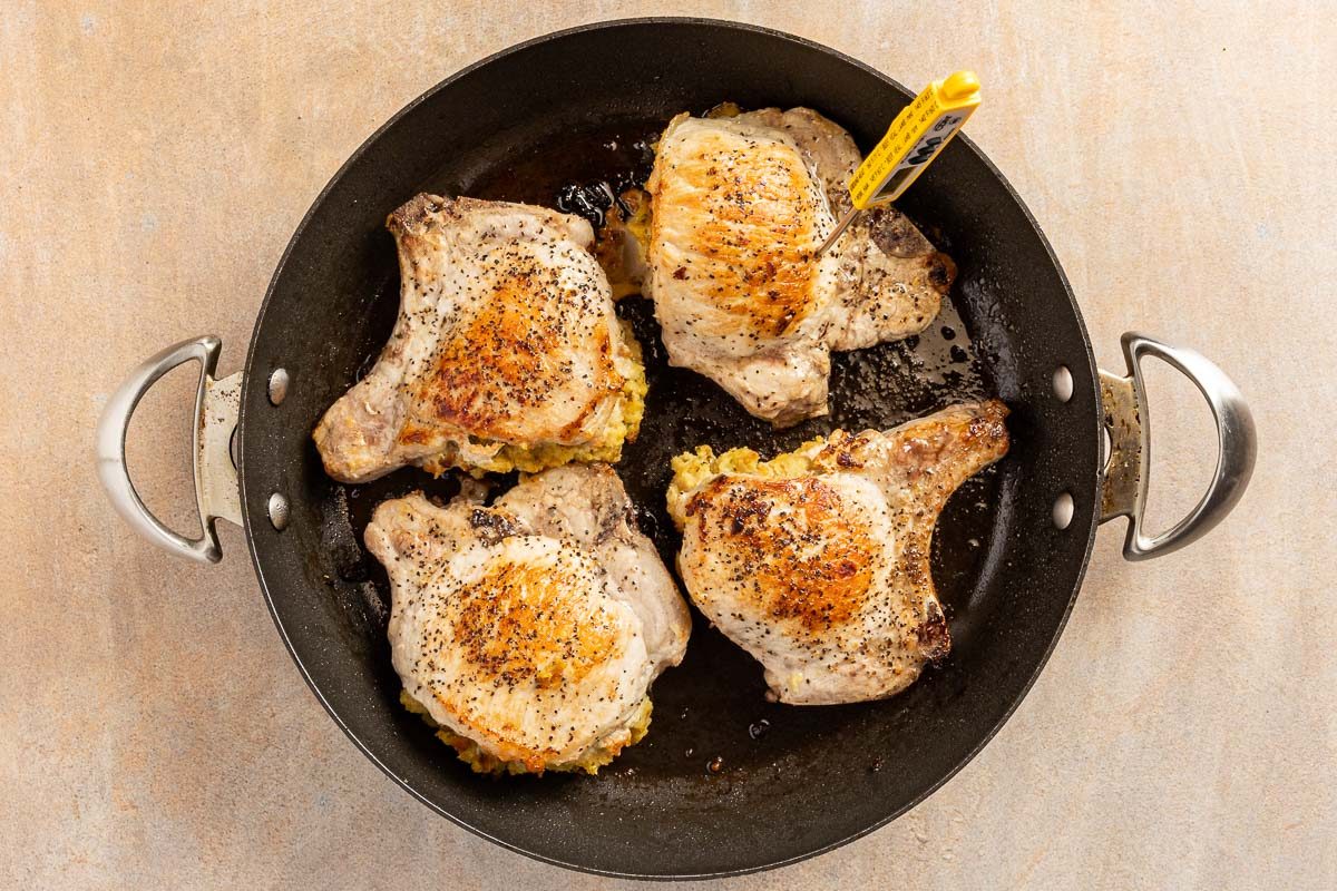 Stuffing Stuffed Pork Chops cooking in a skillet with a thermometer
