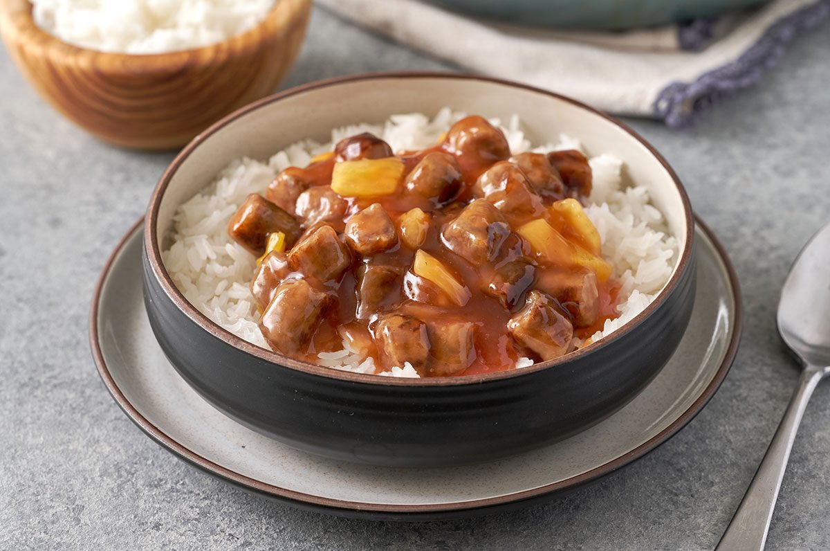 A close-up shot of the Sweet-and-Sour Sausage, highlighting the juicy sausage pieces, pineapple chunks, and the rich sweet-and-sour sauce, by Taste of Home