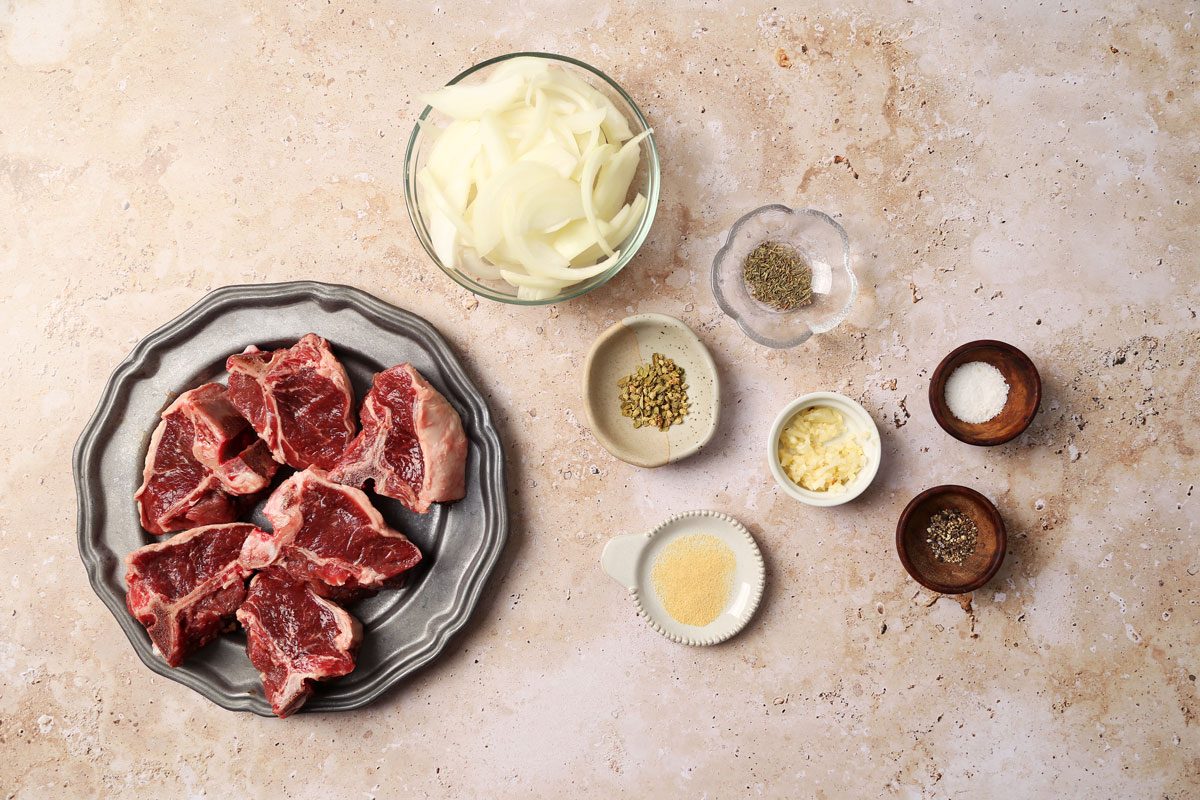 Ingredients for Taste of Home's Slow Cooker Lamb Chops laid out in small bowls on a beige marble surface.