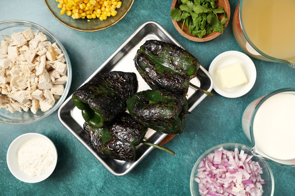 Process of making Taste of Home's Poblano Soup roasted poblanos on a baking sheet on a teal surface.