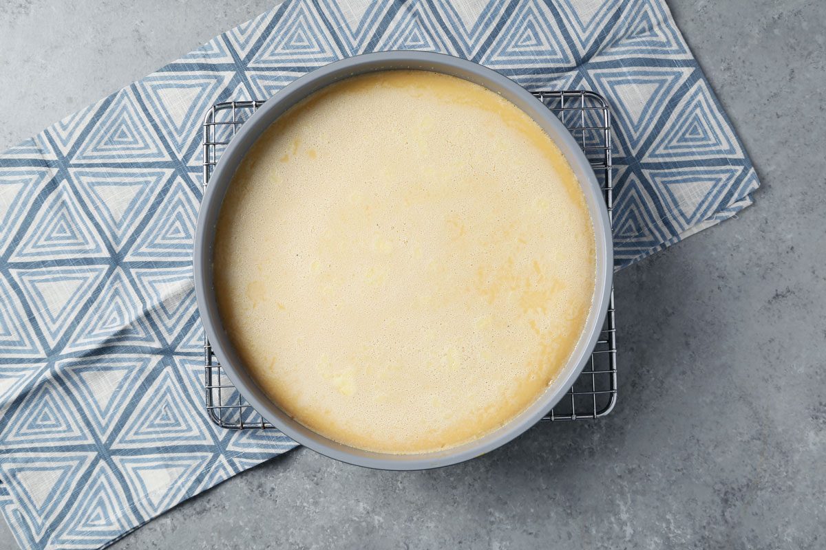 Process of making Taste of Home's Flan de Queso. Flan poured into a baking pan in a roasting pan with water.
