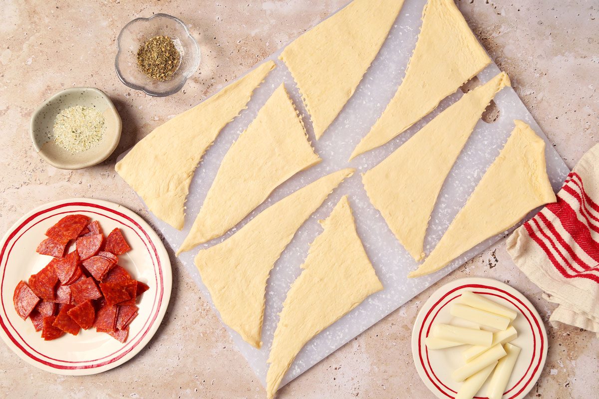 Process of making Taste of Home's Pepperoni Rolls crescent roll dough separated on a brown and beige marble surface.