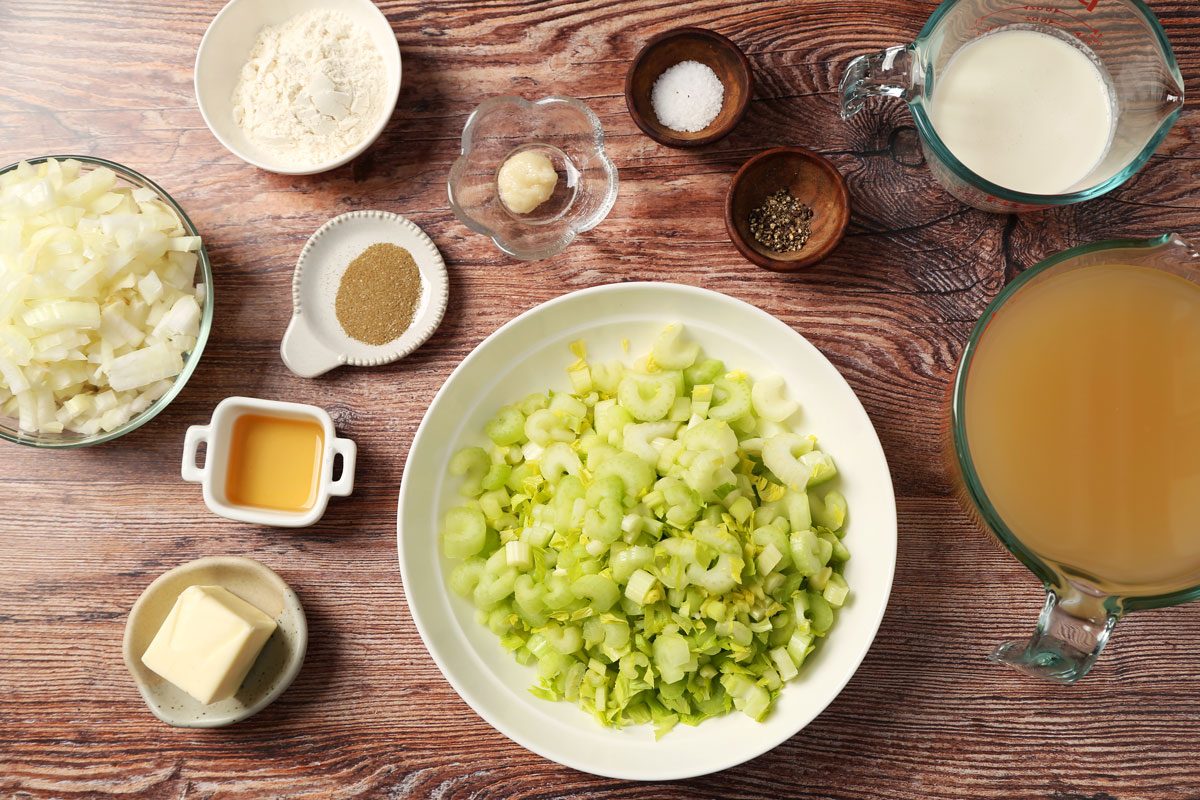 Ingredients for Taste of Home's Cream of Celery Soup laid out in small bowls on brown wooden surface.