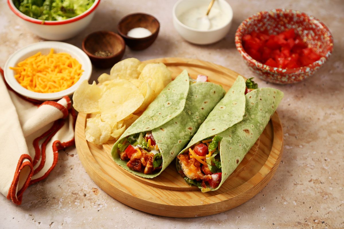 Close up of Taste of Home's Buffalo Chicken Wrap on a wooden serving platter on a beige surface.