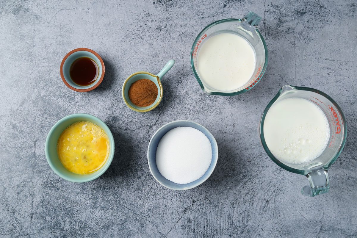 Ingredients for Taste of Home's Cinnamon Ice cream laid out in small bowls on a blue surface.