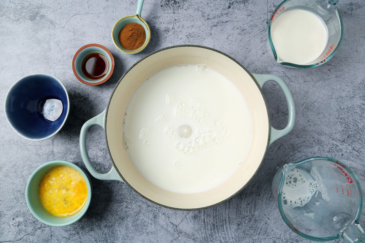 Ingredients for Taste of Home's Cinnamon Ice Cream laid out in small bowls on a blue marble surface.