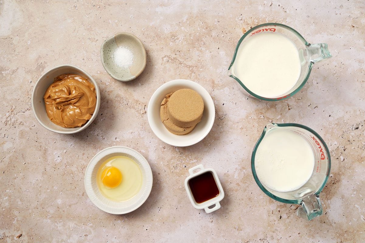 Ingredients for Taste of Home's Peanut Butter Ice Cream laid out in small bowls on a brown marble surface.
