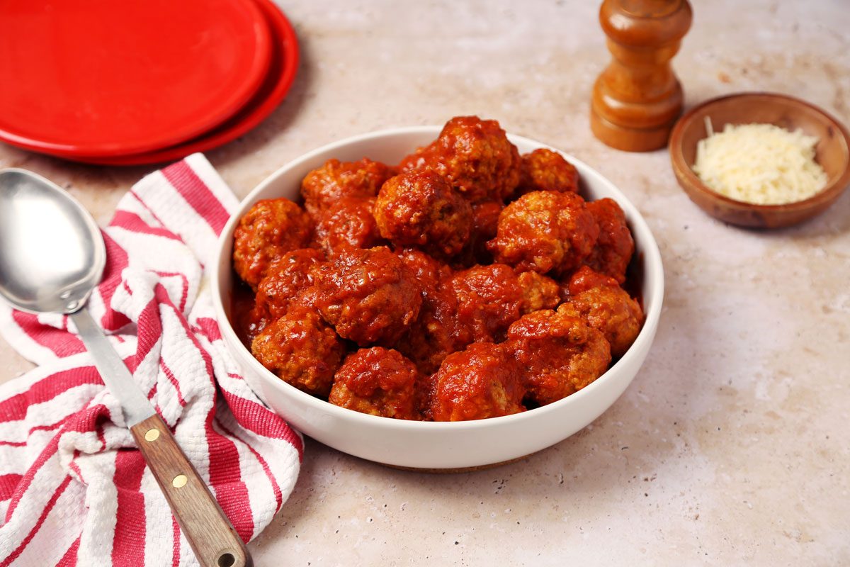 Close up of Taste of Home's Instant Pot Meatballs served in a white serving bowl on a brown marble surface.