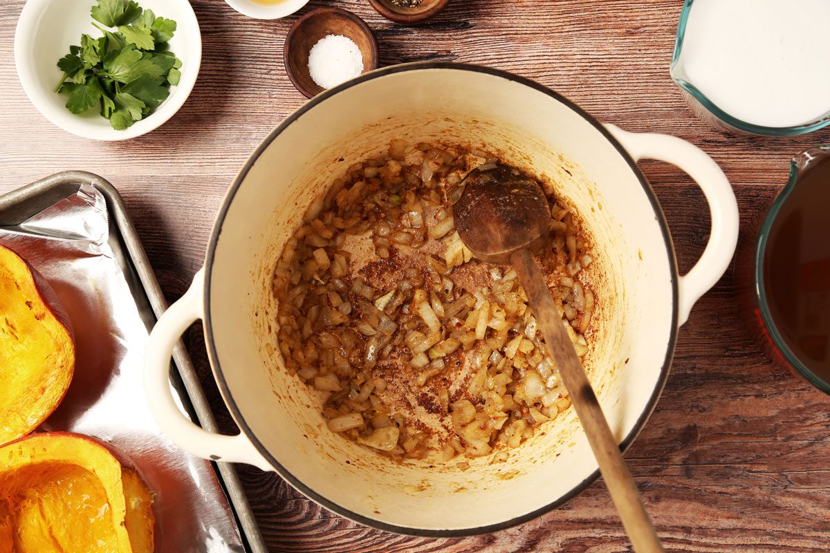 Process of making Taste of Home's Chicken Pumpkin Soup in a dutch oven on a brown wooden surface.