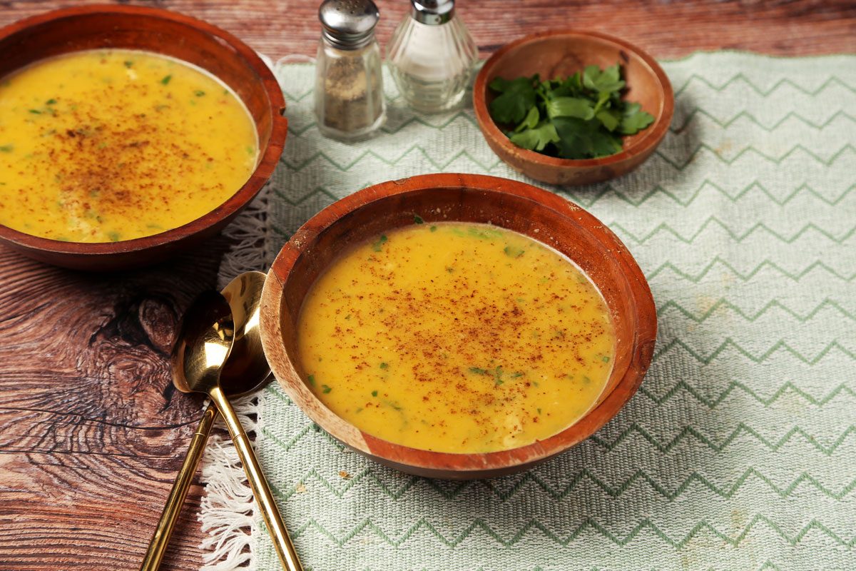 Close up of Taste of Home's Chicken Pumpkin Soup served in wooden bowls on a brown wooden surface.