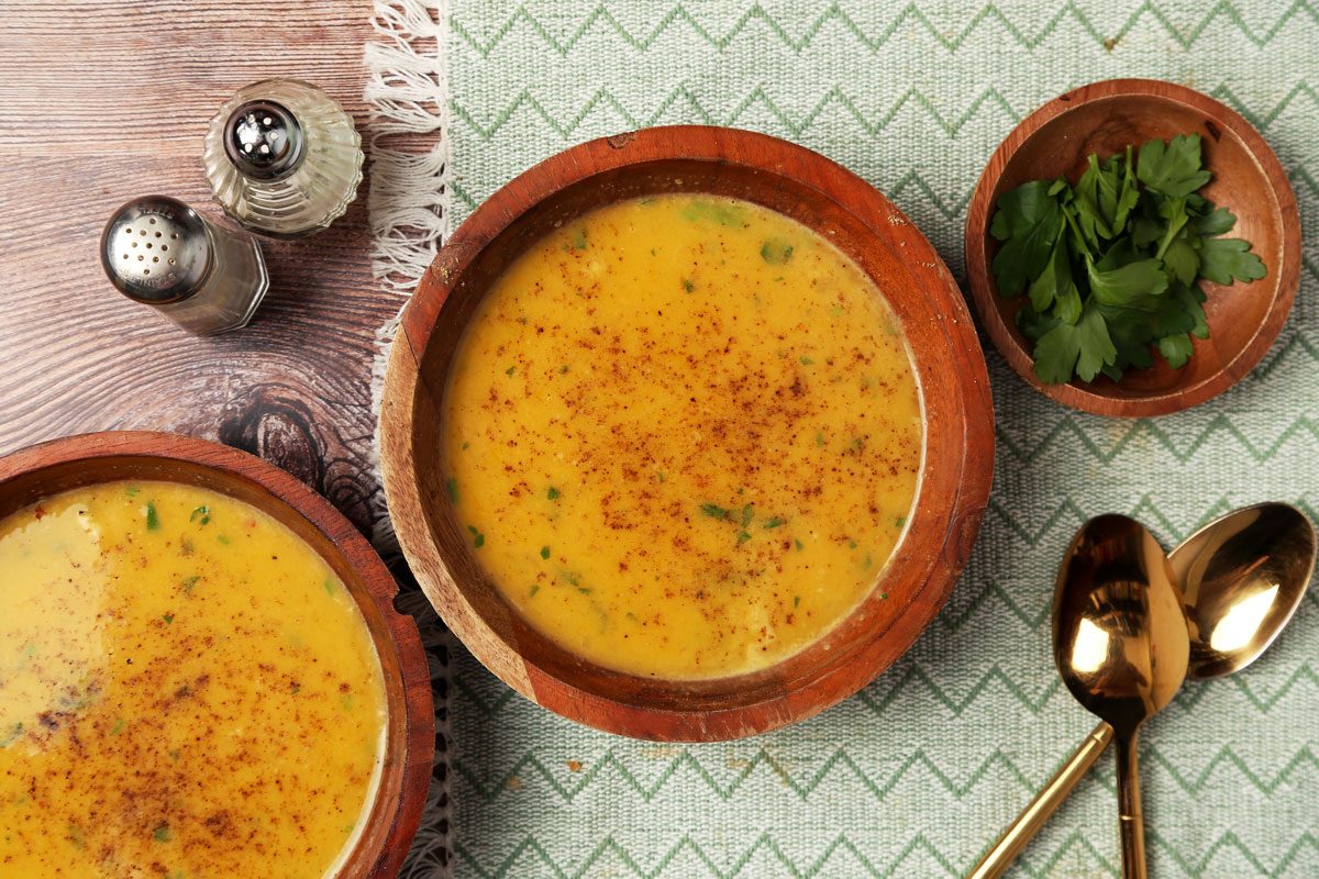 Close up of Taste of Home's Chicken Pumpkin Soup served in wooden bowls on a brown wooden surface.