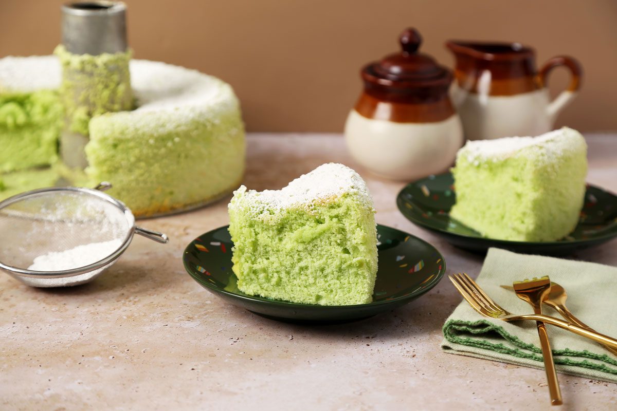 Close up of Taste of Home's Pandan Cake sliced and served on green plates on a brown marble surface.