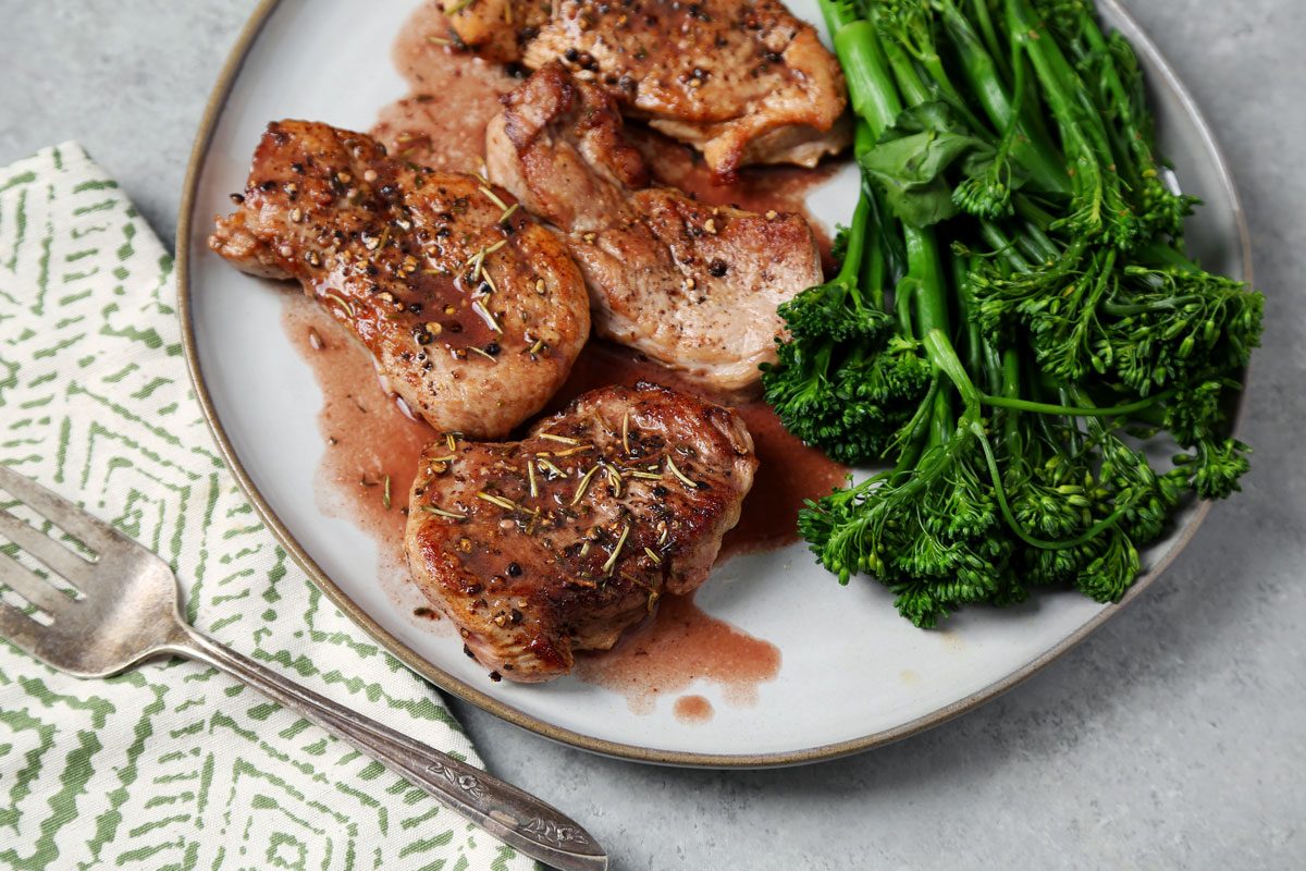 Close up of Taste of Home's Pork and Red Wine Sauce served on a large grey plate on a grey marble surface.