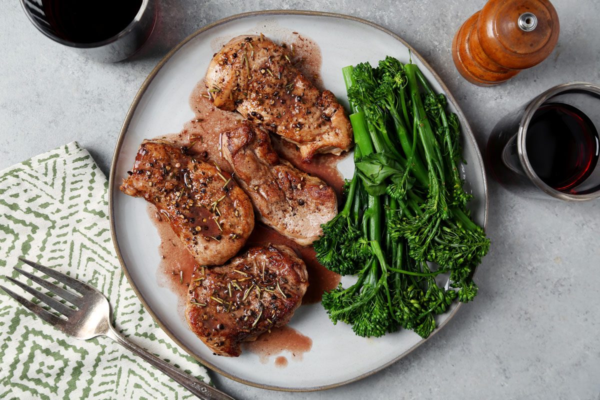 Close up of Taste of Home's Pork and Red Wine Sauce served on a large grey plate on a grey marble surface.