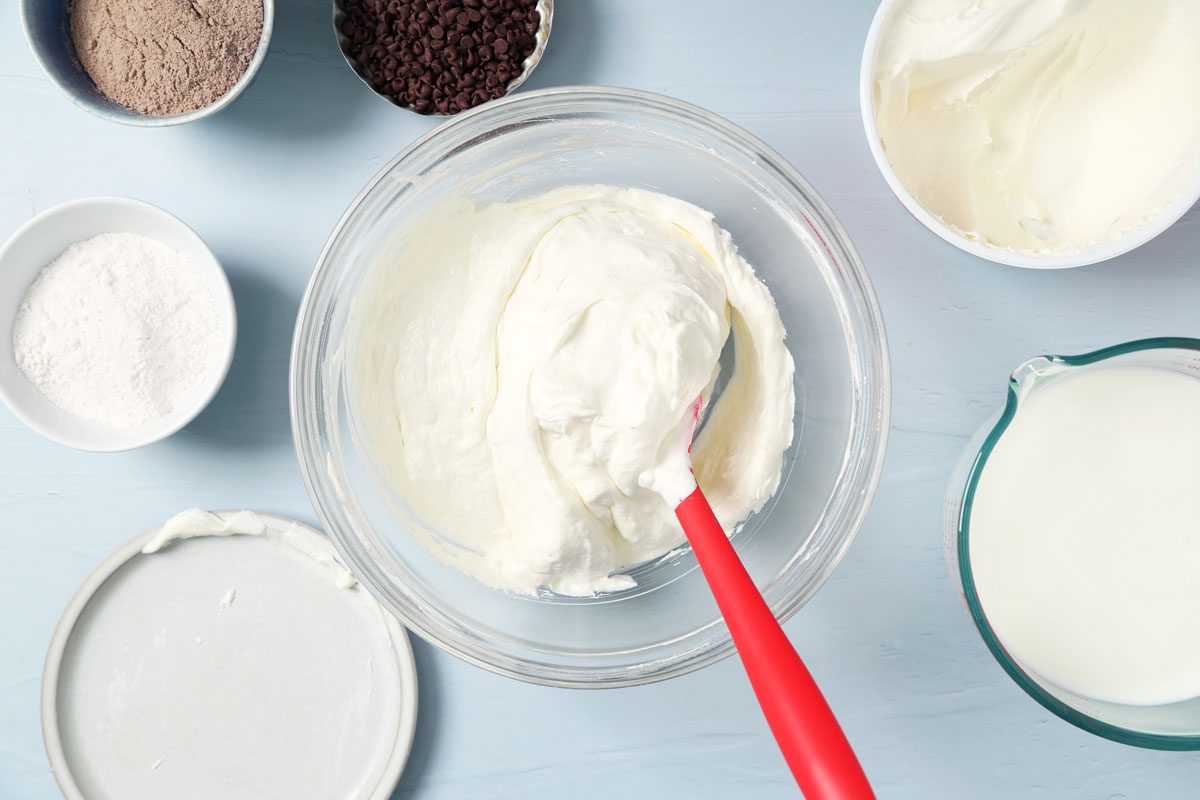 Process of making Taste of Home's Chocolate Chip Cookie Delight in a baking pan on a light blue surface.