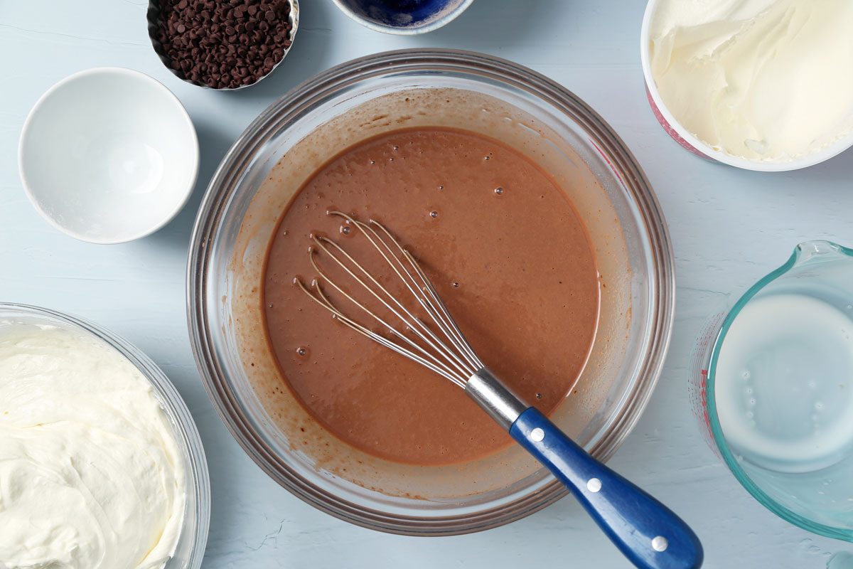 Process of making Taste of Home's Chocolate Chip Cookie Delight in a baking pan on a light blue surface.