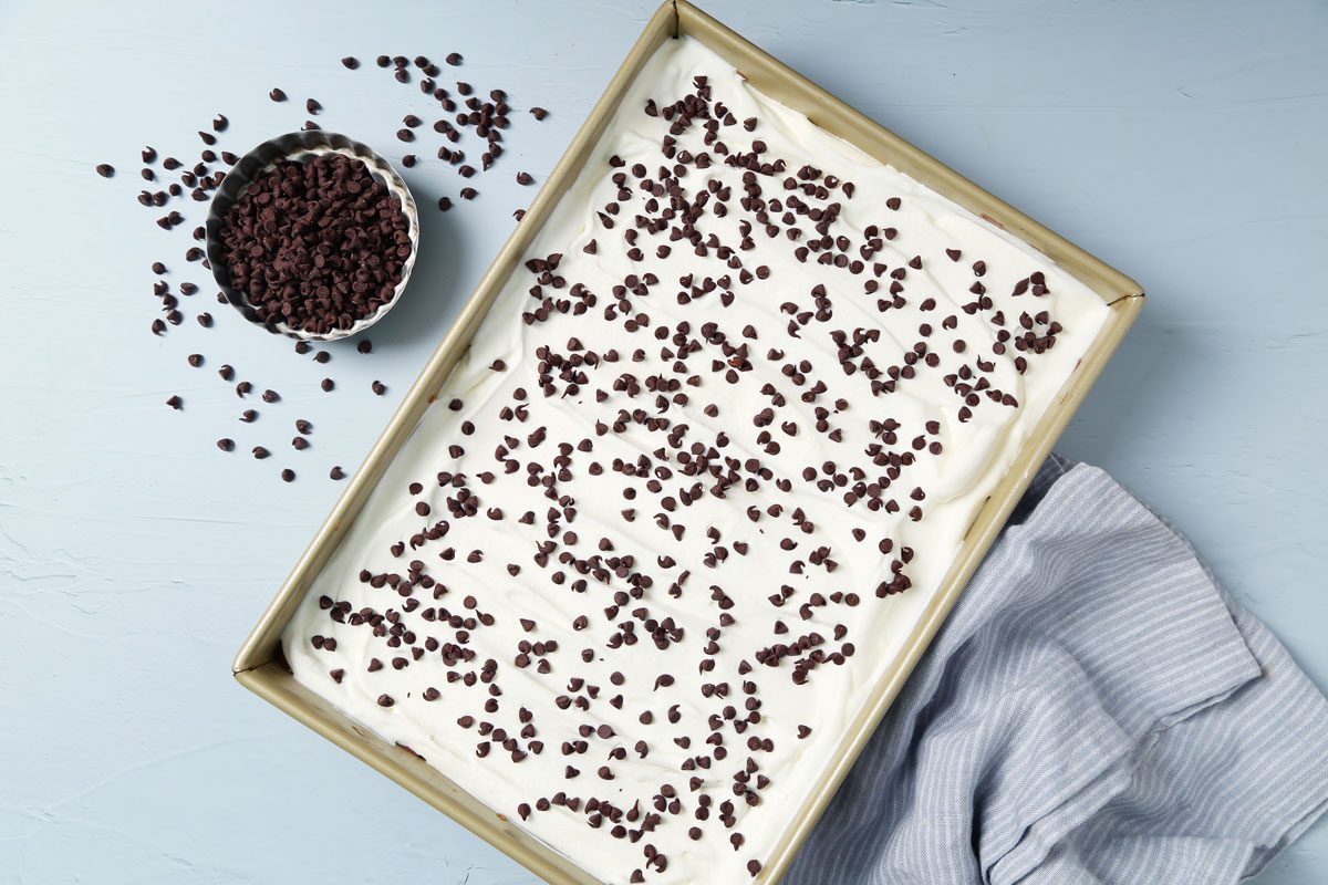 Process of making Taste of Home's Chocolate Chip Cookie Delight in a baking pan on a light blue surface.