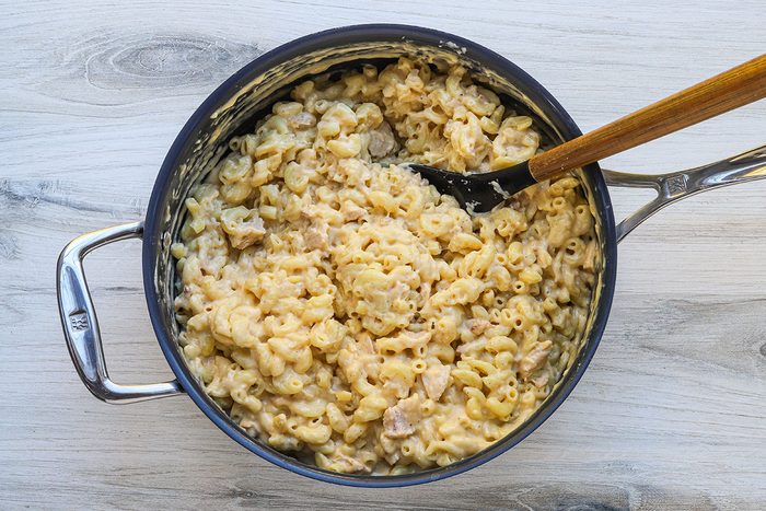 Tuna mac and cheese preparation: combining the macaroni with the cheese sauce.