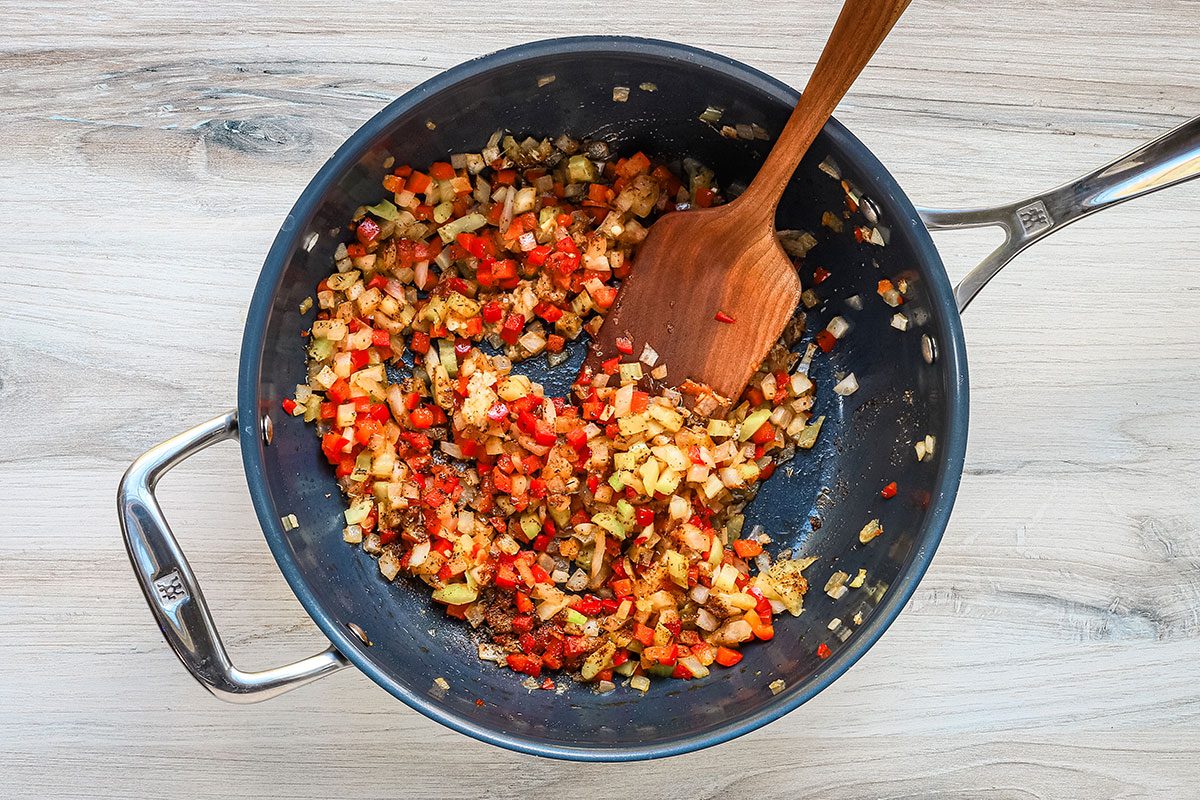 Adding the herbs and spices to the sautéed vegetables.