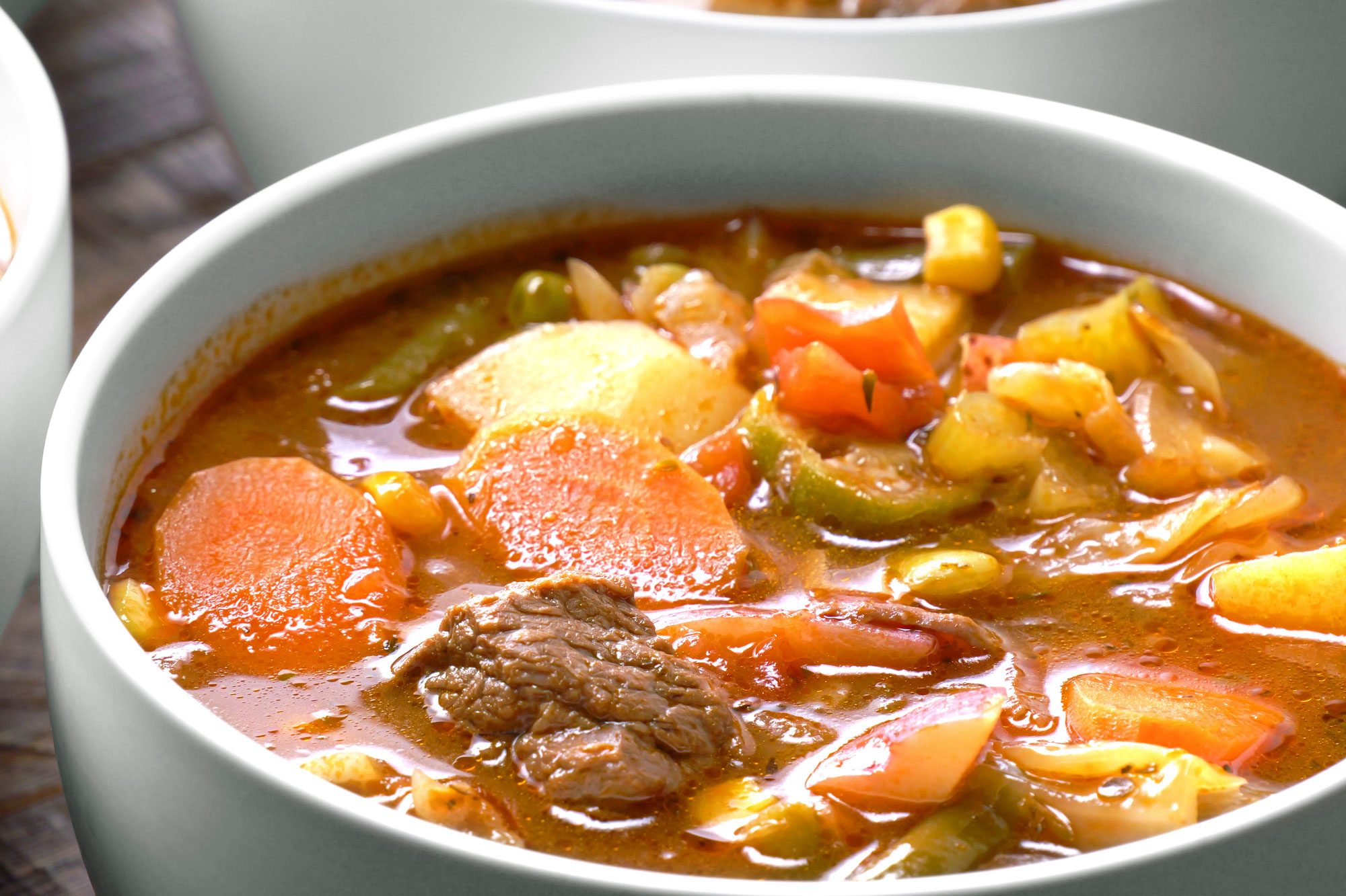A hearty vegetable beef soup are arranged on a wooden table