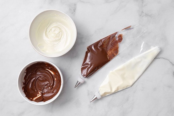 Melted white and chocolate chips in bowls and piping bag for step six of Wookie Cookie recipe for Taste of Home