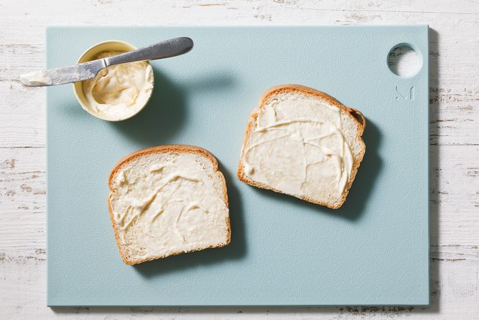 Using a butter knife, spread mayonnaise on both slices of bread.