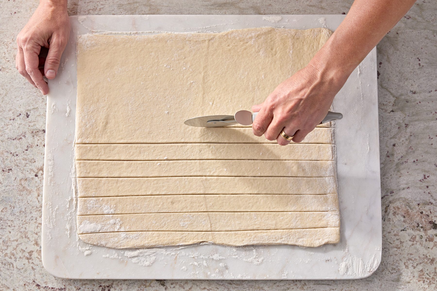 On a floured surface, roll out pizza dough into a large rectangle. Cut each rectangle into 1-inch strips.