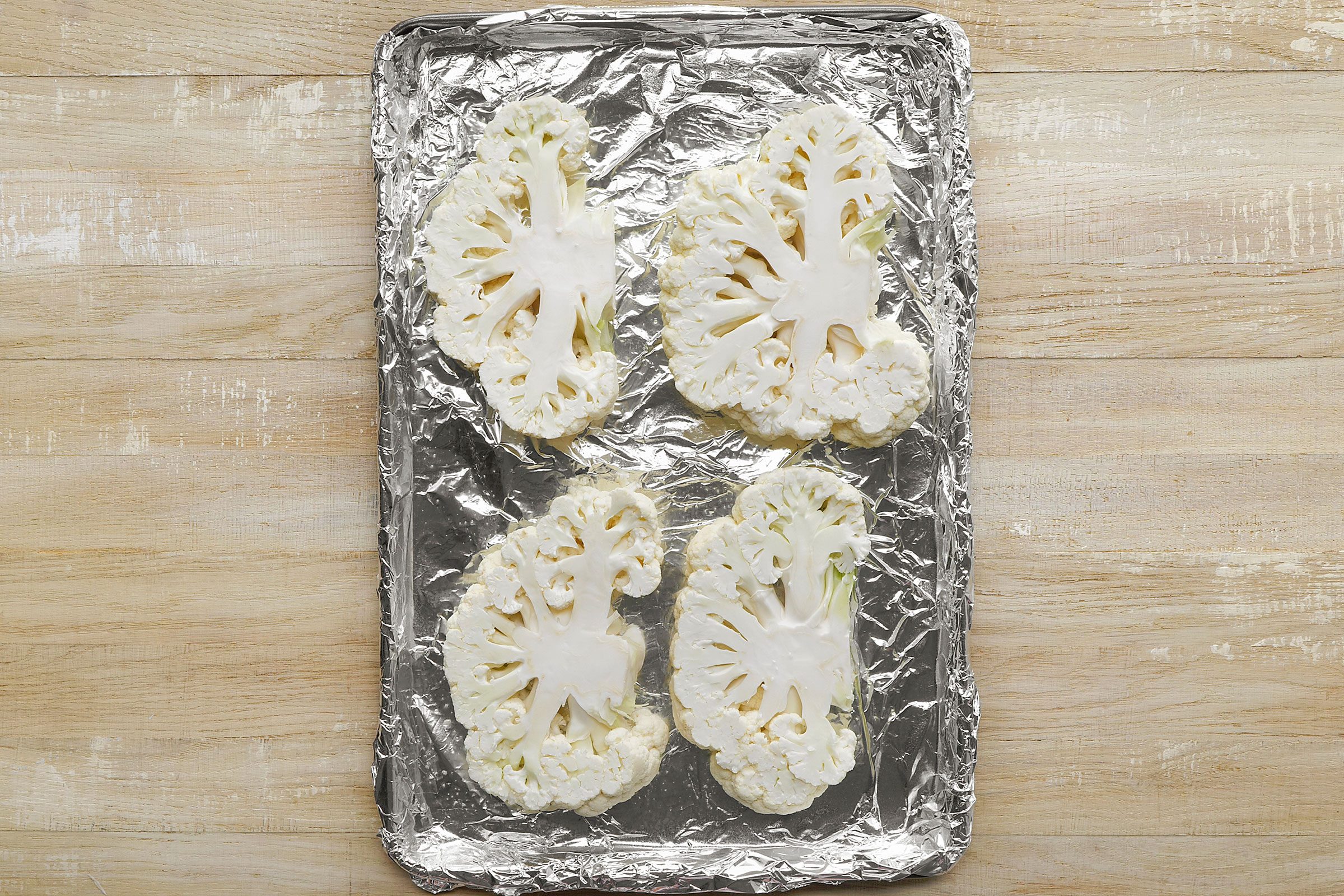 Cauliflower cut into slices and placed on a foil covered baking pan