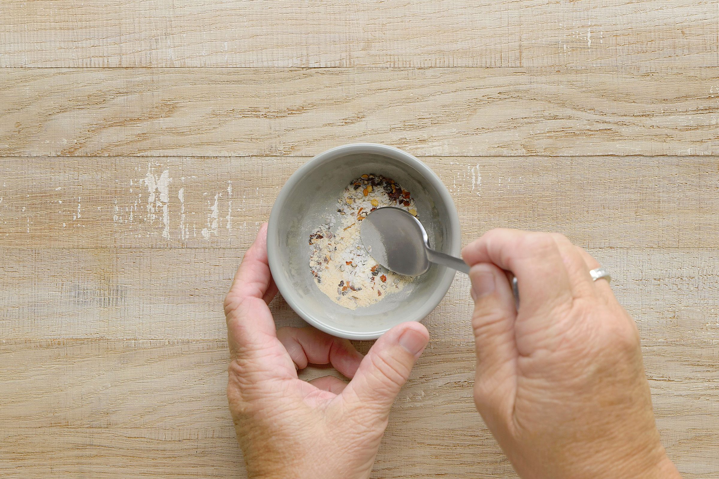 Combining seasoning into a mixture in a small bowl with a spoon